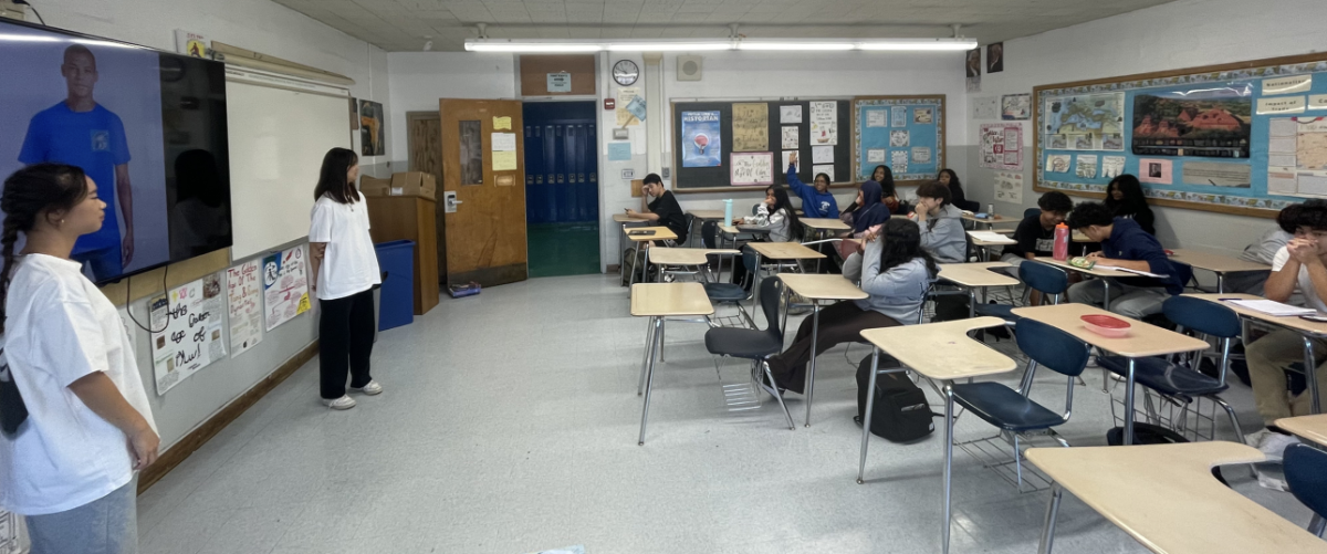 Kitty and Sophie Guan present the "Believe" T-shirts to a social studies class.